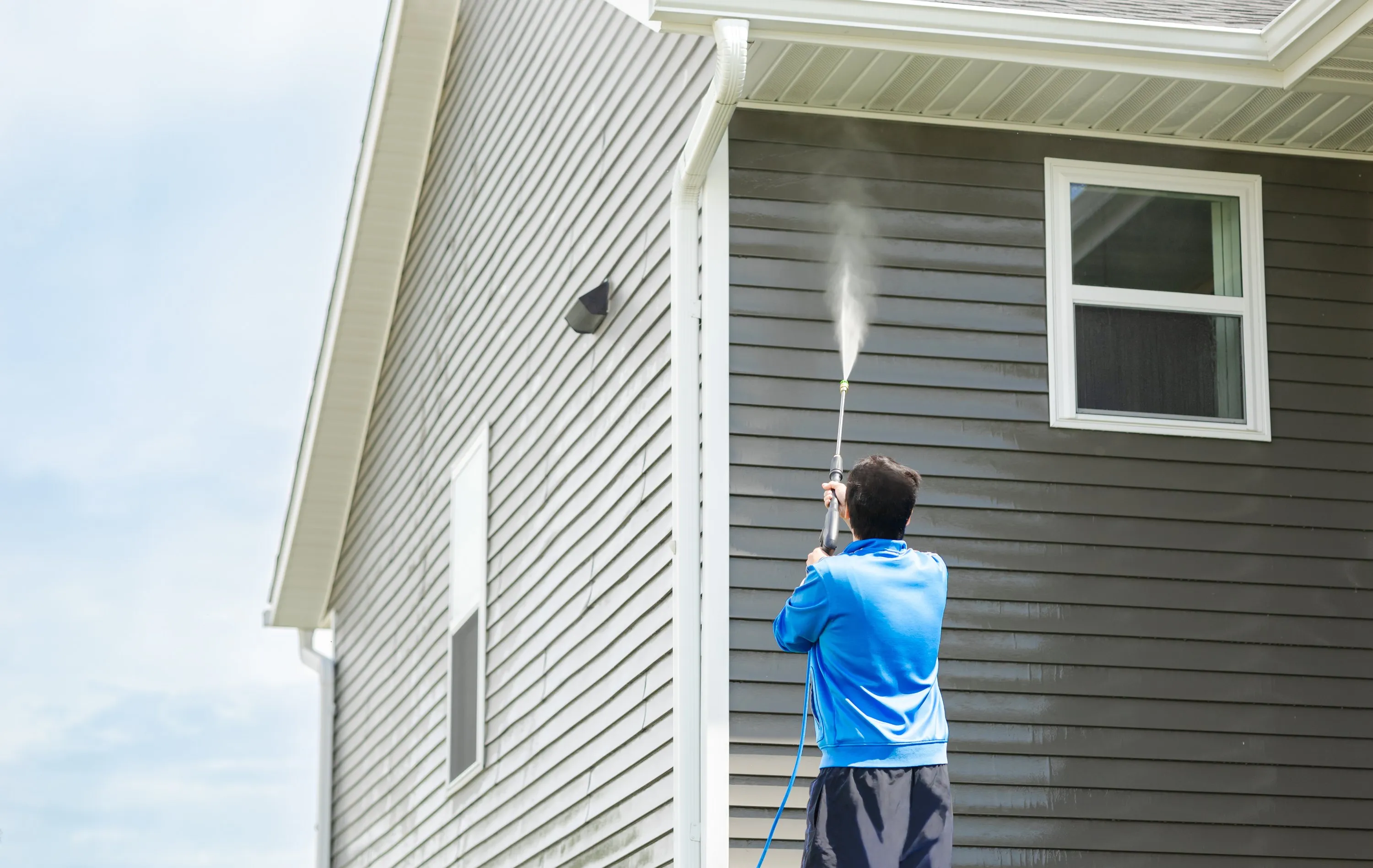 A technician washing the siding of a house